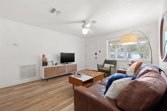 living room with light wood-style floors, baseboards, and visible vents