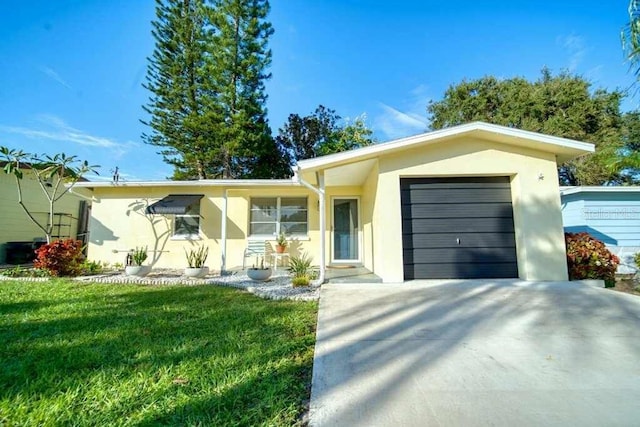 ranch-style home featuring driveway, a front yard, an attached garage, and stucco siding