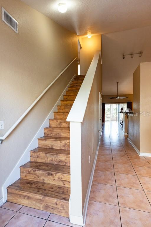 stairs featuring tile patterned floors and ceiling fan