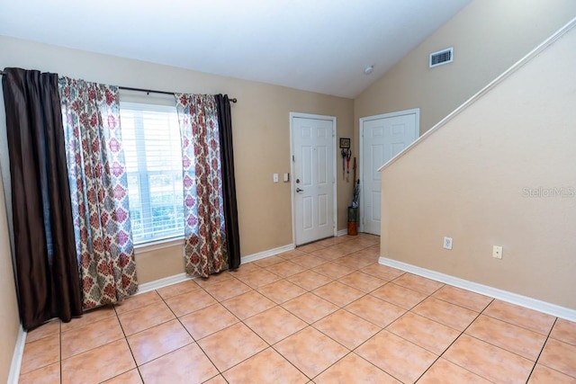 spare room with light tile patterned flooring and lofted ceiling