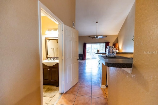 hall featuring light tile patterned flooring, vaulted ceiling, and sink