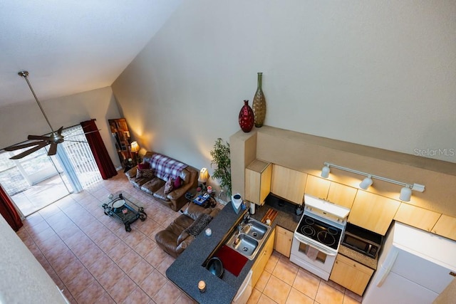 living room with light tile patterned flooring, ceiling fan, rail lighting, and vaulted ceiling