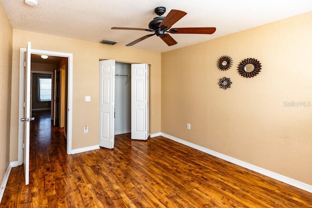 unfurnished bedroom with dark hardwood / wood-style flooring, a textured ceiling, a closet, and ceiling fan