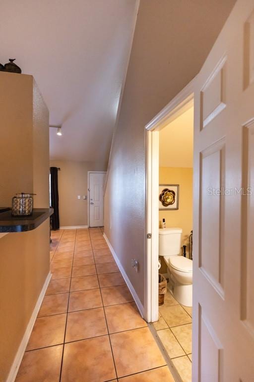 hallway featuring light tile patterned floors and vaulted ceiling