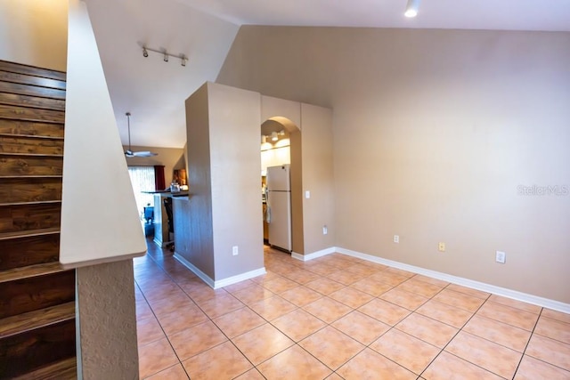 empty room featuring rail lighting, lofted ceiling, and light tile patterned floors