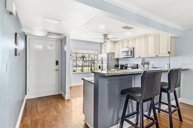 kitchen featuring light wood-style flooring, visible vents, stainless steel appliances, and a breakfast bar area