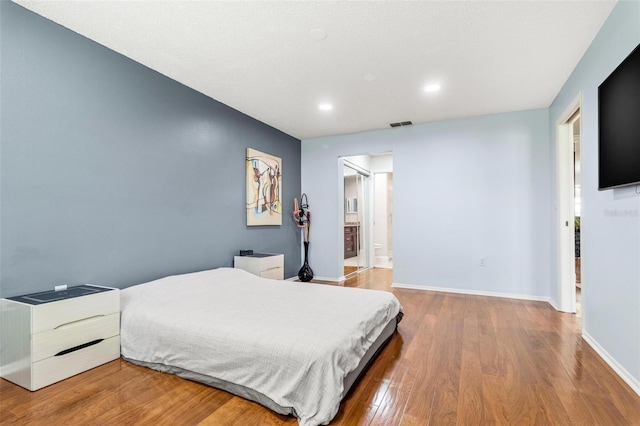 bedroom with recessed lighting, visible vents, baseboards, and wood finished floors