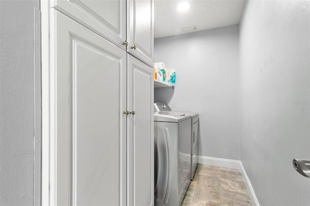 laundry room with washing machine and clothes dryer, cabinet space, and baseboards