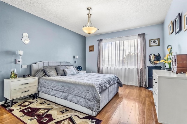 bedroom featuring light wood-style flooring, baseboards, and a textured ceiling