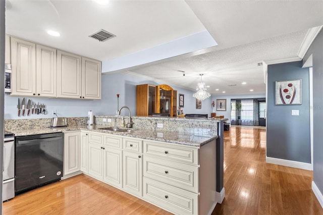 kitchen featuring light wood-style flooring, stainless steel appliances, a peninsula, a sink, and open floor plan