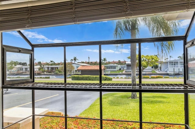 unfurnished sunroom featuring a water view and a residential view