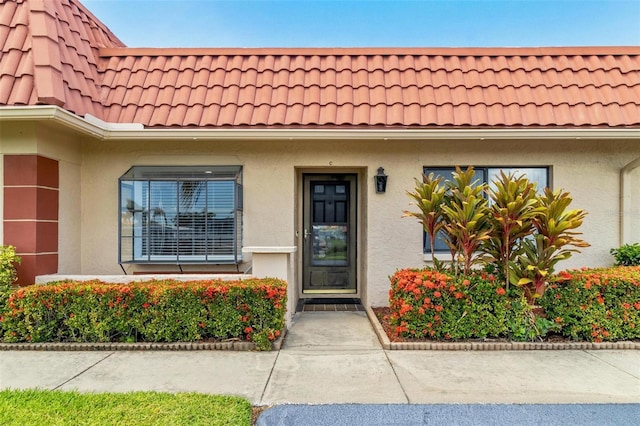 view of exterior entry featuring a tiled roof and stucco siding