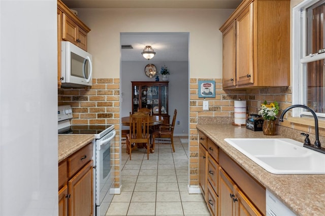 kitchen featuring white appliances, sink, and light tile patterned floors