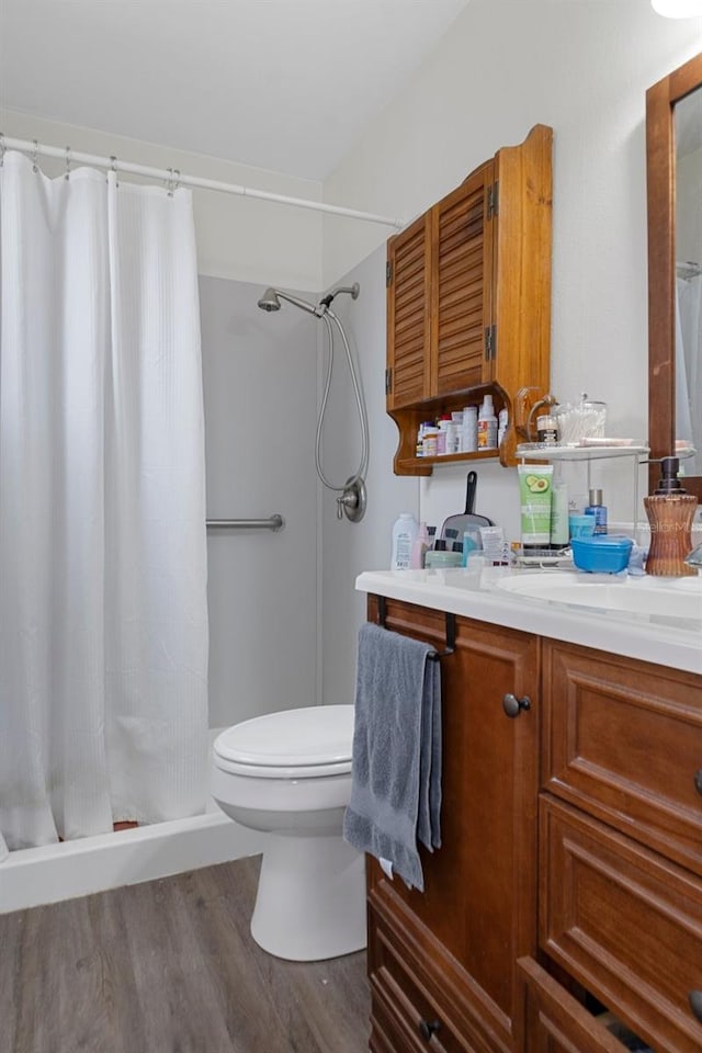 bathroom featuring wood-type flooring, toilet, a shower with shower curtain, and vanity