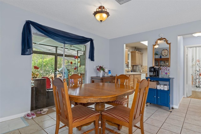 dining space with sink, light tile patterned floors, and a textured ceiling