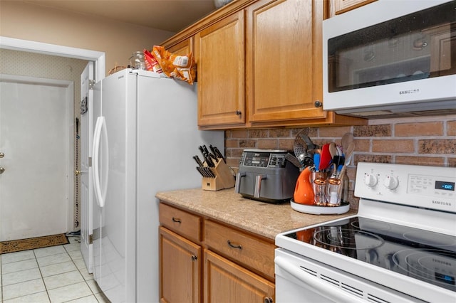 kitchen with light tile patterned floors, white appliances, and decorative backsplash