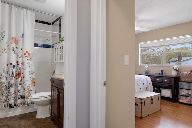 full bathroom with hardwood / wood-style flooring, vanity, toilet, shower / bathtub combination with curtain, and a textured ceiling