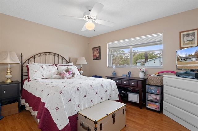 bedroom with ceiling fan, light hardwood / wood-style flooring, and a textured ceiling