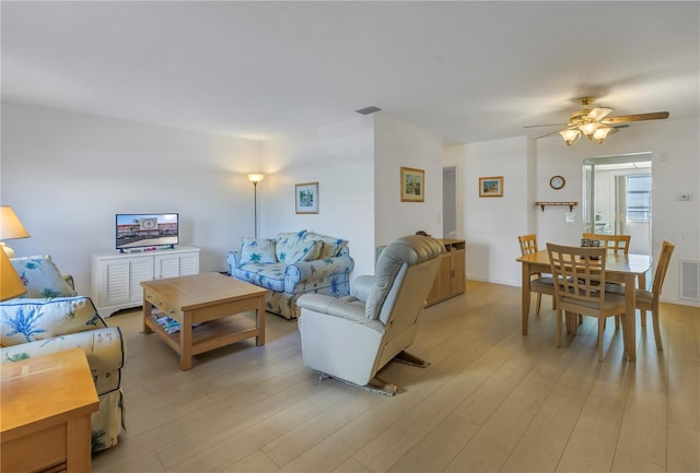 living area featuring light wood-type flooring, visible vents, and a ceiling fan