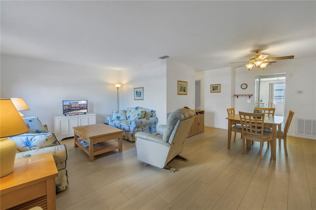 living room with light wood-type flooring, visible vents, and ceiling fan