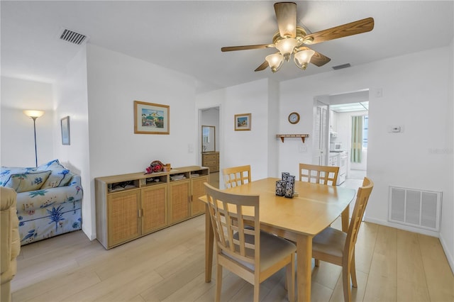 dining room featuring light wood finished floors, visible vents, and a ceiling fan