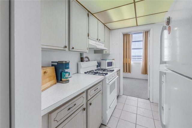 kitchen with light tile patterned floors, light countertops, white appliances, and under cabinet range hood