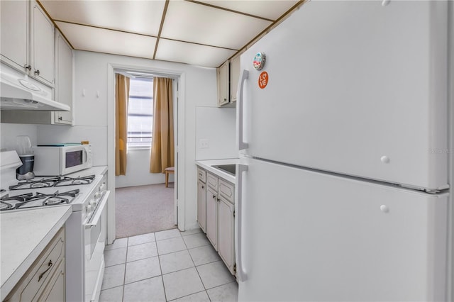 kitchen featuring light tile patterned floors, light countertops, white appliances, and under cabinet range hood