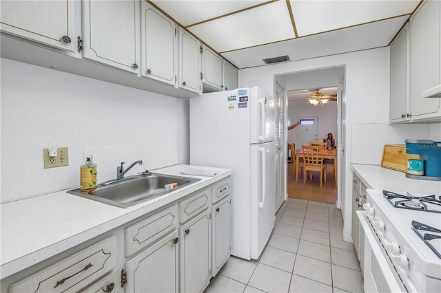 kitchen featuring light tile patterned flooring, white appliances, a sink, visible vents, and light countertops