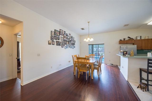 dining area with dark hardwood / wood-style flooring, a notable chandelier, and vaulted ceiling