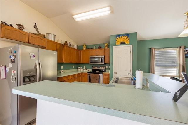 kitchen with vaulted ceiling, pendant lighting, sink, kitchen peninsula, and stainless steel appliances