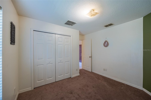 unfurnished bedroom with carpet floors, a textured ceiling, and a closet