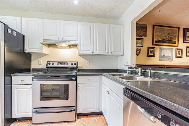 kitchen featuring sink, light tile patterned floors, appliances with stainless steel finishes, white cabinetry, and a textured ceiling