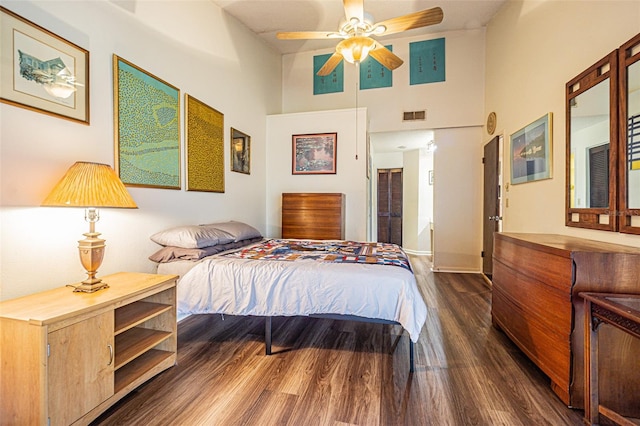 bedroom featuring dark hardwood / wood-style floors, ceiling fan, and a towering ceiling