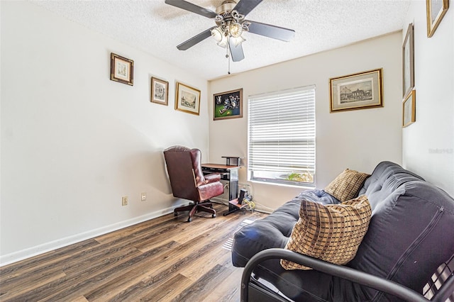 living area featuring wood-type flooring, ceiling fan, and a textured ceiling