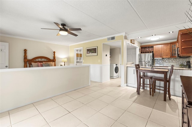 interior space with washer / dryer, light tile patterned floors, ornamental molding, stainless steel fridge, and ceiling fan