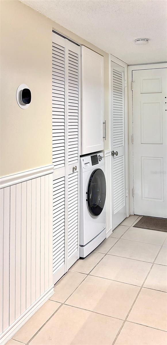 washroom with washer / dryer, cabinets, a textured ceiling, and light tile patterned flooring