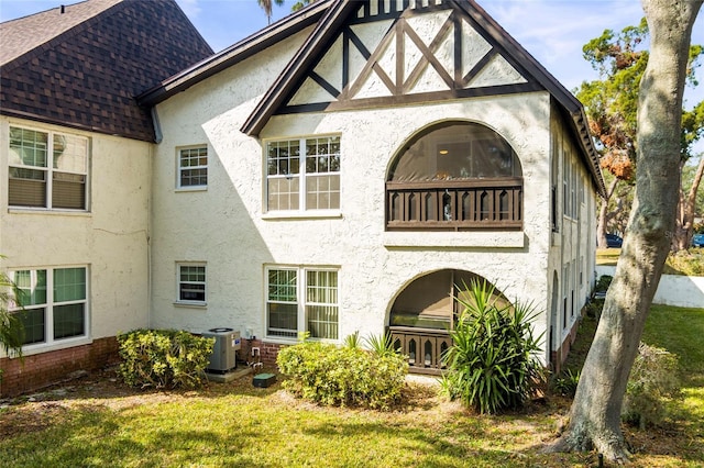 back of house with central AC unit and a lawn