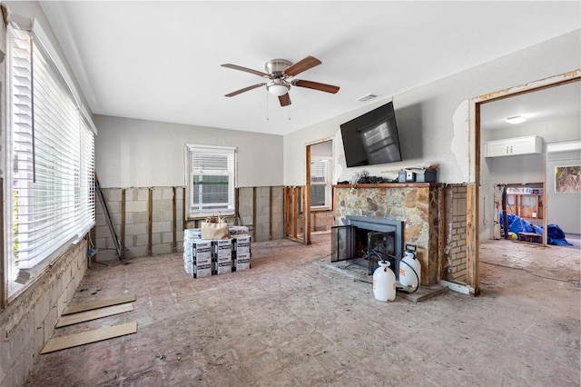 living room with a stone fireplace and ceiling fan