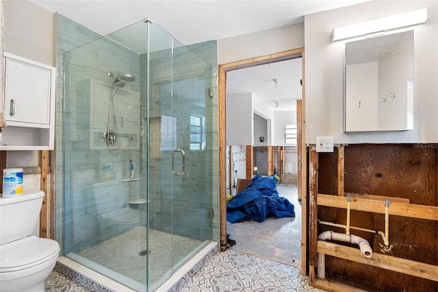 bathroom featuring a shower with shower door and toilet