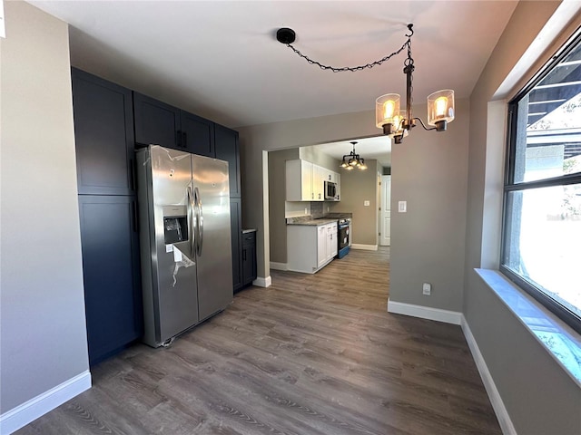 kitchen featuring dark wood-style flooring, a notable chandelier, stainless steel appliances, white cabinetry, and baseboards