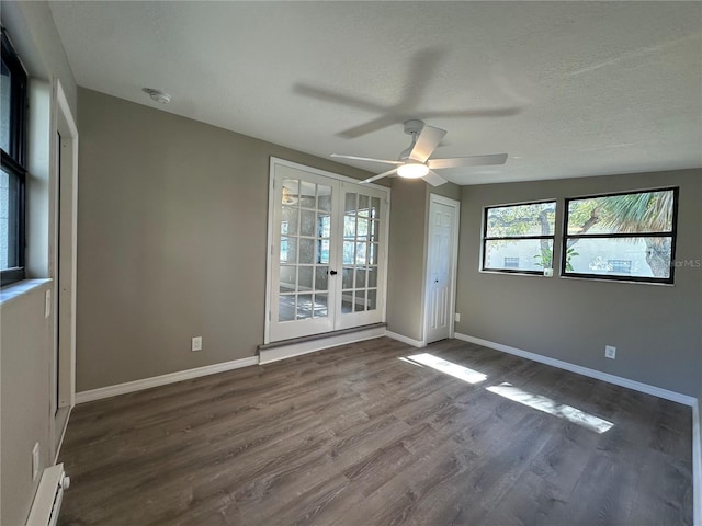 unfurnished room featuring a baseboard radiator, baseboards, dark wood-type flooring, and french doors