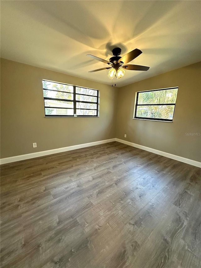 empty room with dark wood-style flooring, plenty of natural light, and baseboards