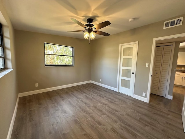 unfurnished bedroom featuring ceiling fan, dark wood finished floors, visible vents, and baseboards