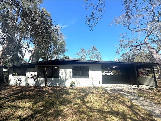 view of front of house with concrete driveway, an attached carport, and a front yard