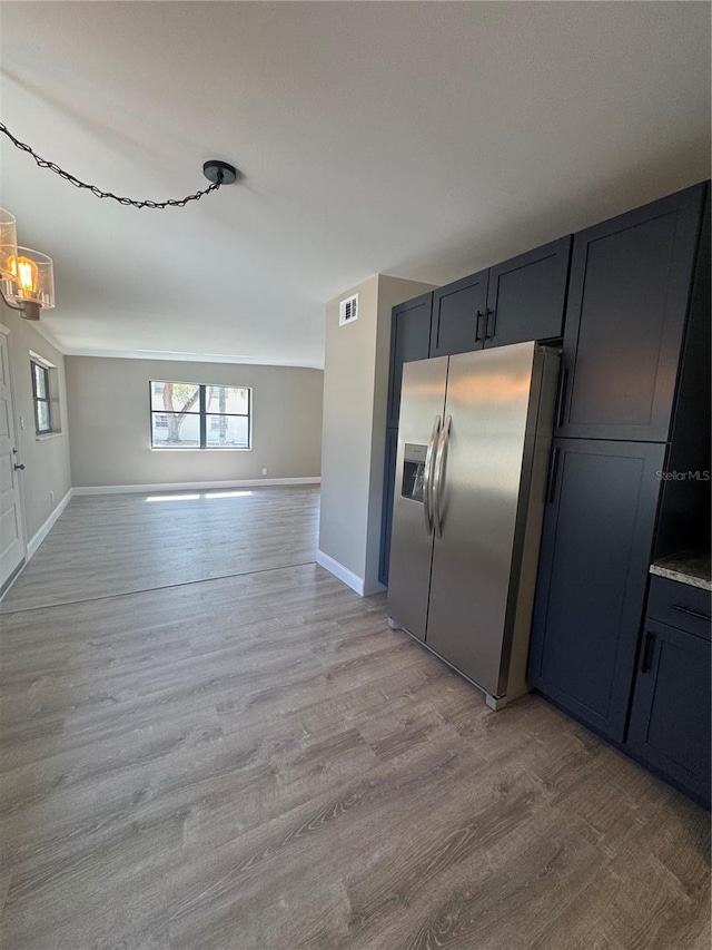 kitchen featuring open floor plan, light wood-style flooring, visible vents, and stainless steel fridge with ice dispenser