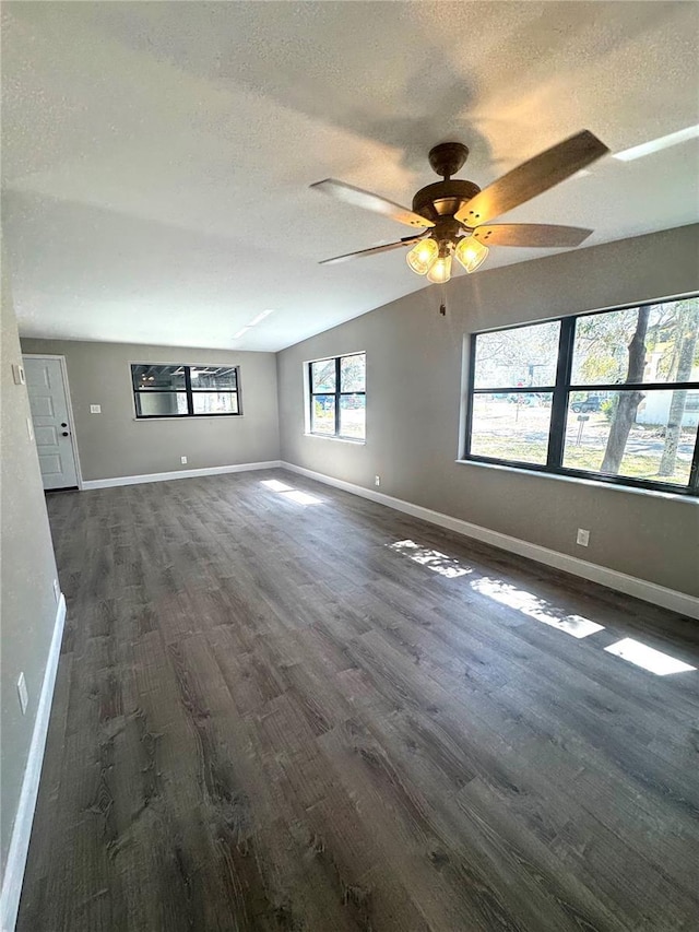 empty room featuring a textured ceiling, baseboards, vaulted ceiling, and dark wood-type flooring