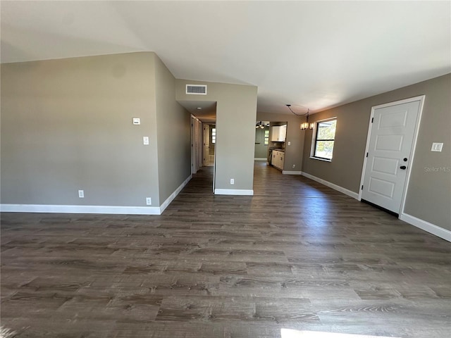 unfurnished living room with visible vents, baseboards, dark wood finished floors, an inviting chandelier, and vaulted ceiling