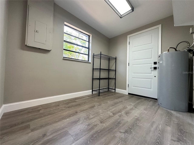 interior space with electric panel, water heater, baseboards, and wood finished floors