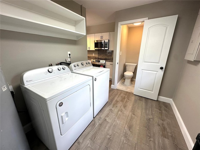 clothes washing area featuring light wood finished floors, independent washer and dryer, and baseboards