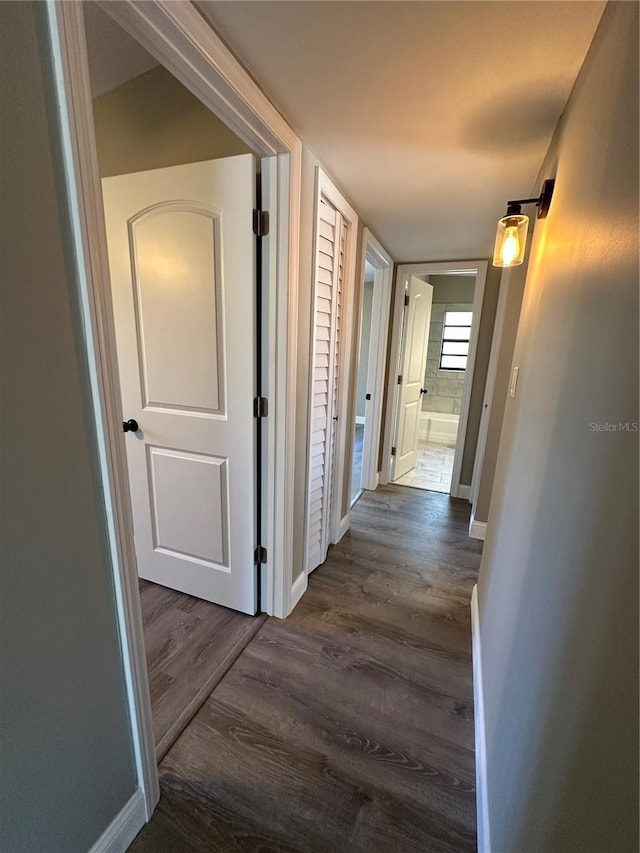 hallway featuring dark wood-style flooring and baseboards